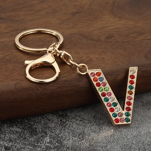 Macro detail of golden letter V keychain featuring colorful rhinestones and lobster clasp