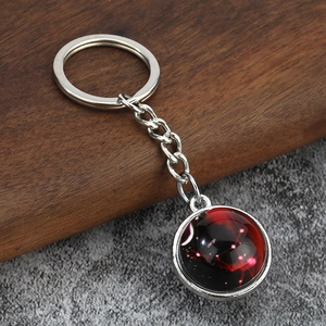 Close-up of luminous Virgo zodiac keychain with a glowing red starry nebula glass pendant