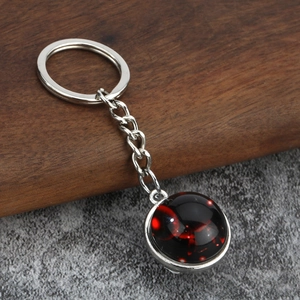 Close-up of luminous zodiac keychain featuring a red nebula glass ball with silver metal ring
