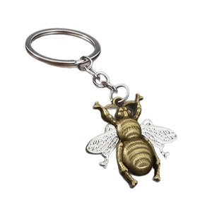Minimalist bee keychain in vintage bronze and silver metal on a clean white background