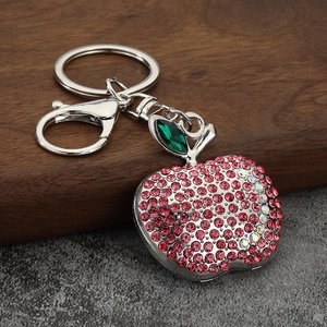 Close-up of apple keychain with red rhinestones and green leaf on wooden background