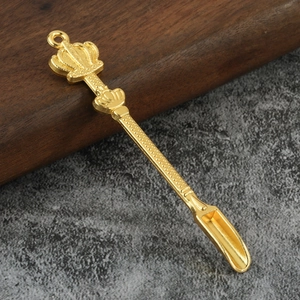 Golden crown mini spoon pendant with textured handle on dark stone and wood background