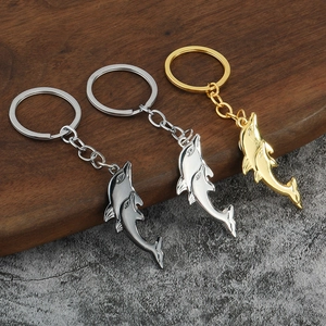 Gepolijste dolfijn sleutelhangers in gunmetal, zilver en goud op een textuur basis