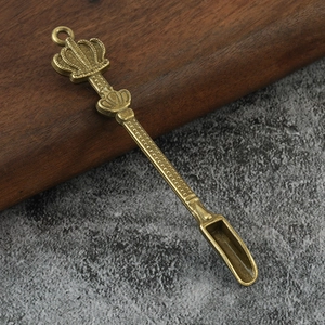 Detail of vintage crown-shaped metal snuff spoon with textured handle and bronze finish