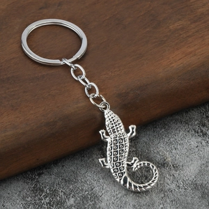 Macro shot of silver metal crocodile keychain with textured scales on a rustic wood base