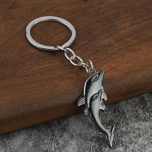 Macro detail van de gunmetal dolfijn sleutelhanger met metaaltextuur op stenen achtergrond