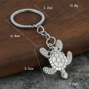 Polished silver alloy sea turtle keychain with detailed shell texture on a rustic background