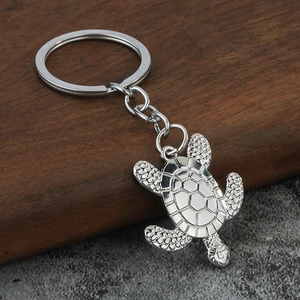 Close-up of a silver sea turtle keychain with detailed shell texture on a wood block