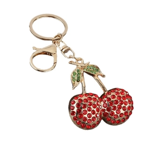 Sparkling red cherry keychain with gold alloy frame and crystal rhinestones on white base