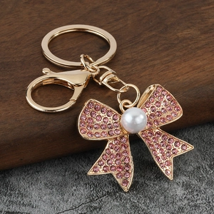 Close-up of pink rhinestone bow keychain with white pearl on golden metal base