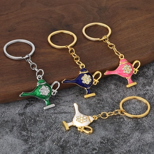 Detail of four colorful Aladdin lamp keychains with rhinestones on a dark wood background