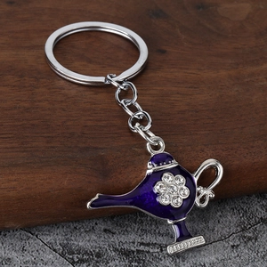 Macro shot of purple Aladdin lamp keychain with white rhinestones on dark wooden surface