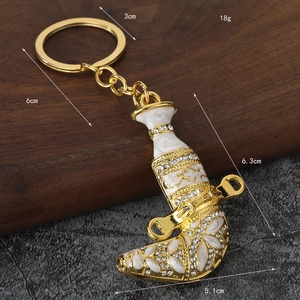 Golden Jambiya dagger keychain with white enamel and rhinestones on walnut wood base