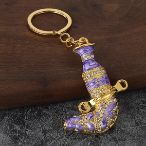 Detailed close-up of a golden Arabian Jambiya dagger keychain with purple enamel and crystals