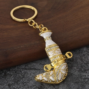 Detailed view of golden Oman Khanjar dagger keychain with white enamel and rhinestones