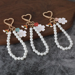 Detail of beaded pearl keychains with heart clasps and colorful enamel flower pendants