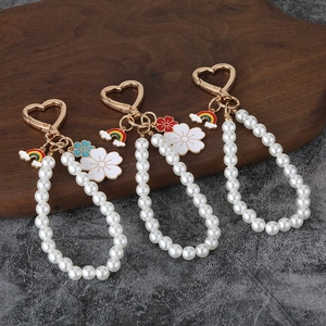 Detailed set of three pearl keychains with golden heart clasps and flower pendants