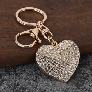 Golden heart keychain with sparkling white rhinestones and lobster clasp on wood