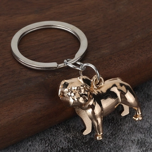 Detailed close-up of a golden bulldog metal keychain on a textured minimalist background