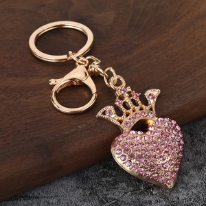 Vista macro di portachiavi corona cuore dorato con strass rosa su base di legno