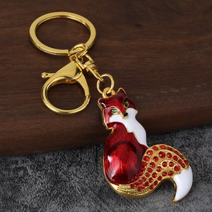 Detail of fox keychain with red enamel coating and crystal-embellished tail on gold metal