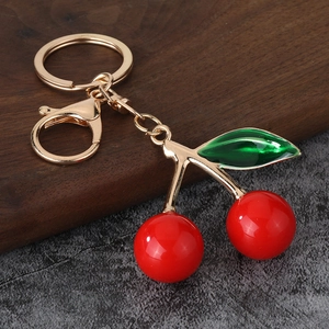 Detailed view of creative cherry keychain with red spheres and green enamel leaf charm