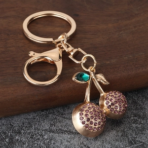 Macro detail of purple rhinestone cherry keychain with golden alloy lobster clasp