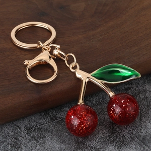 Detailed view of the gold-toned metal keyring with cherry pendant and lobster clasp
