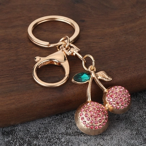 Detail of gold cherry keychain with pink rhinestones and green crystal leaf charm