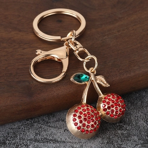 Detailed close-up of crystal cherry keychain with red rhinestones and gold clasp