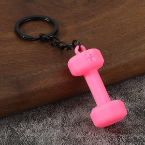 Close-up of a pink 45 LB dumbbell keychain with black metal chain on a wooden desk