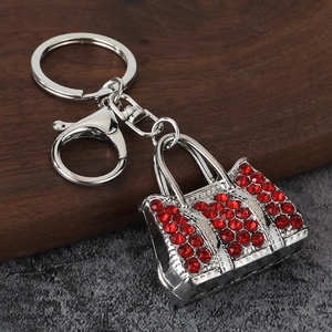 Detailed view of silver handbag keychain with vibrant red rhinestones on a dark wood surface