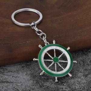 Vue macro d'un porte-clés gouvernail argenté avec émail vert sur fond de bois rustique