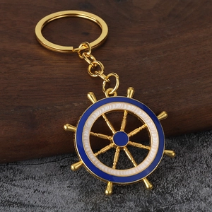 Détail d'un porte-clés gouvernail doré avec émail bleu et blanc sur un support en bois