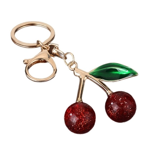 Minimalist red cherry keychain with glitter accents and gold plating on a white background