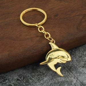 Polished golden shark pendant keychain with dynamic metallic finish on a textured background