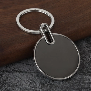 Close-up of circular metal bottle opener keychain with black finish on stone background