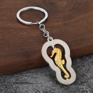 Detail of a metal seahorse keychain featuring a silver frame and golden embossed seahorse