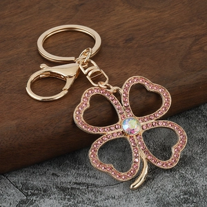 Golden clover keychain with pink crystals and shimmering center stone on marble
