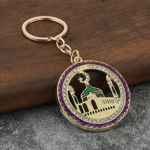 Detail of a gold mosque keychain with purple rim and rhinestones on a wooden background