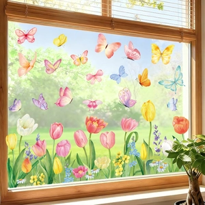 Détail de stickers électrostatiques papillons et tulipes sur vitre avec vue jardin