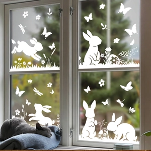 Stickers de Pâques avec lapins et œufs blancs sur vitre avec un chat qui dort