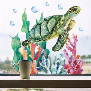 Detail of sea turtle and coral stickers applied on a glass window with a beach view