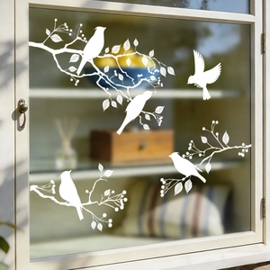 Detail of white bird and branch static window clings on glass in a cozy home setting