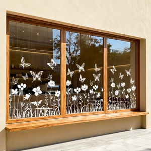 Detailansicht der weißen Blumen- und Schmetterlings-Fensteraufkleber auf einer Glasfläche