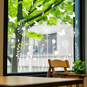Détail de stickers électrostatiques blancs papillon et pissenlit sur une vitre en verre