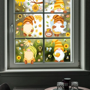 Detail of bee gnome window clings with sunflowers and honey jar on glass surface