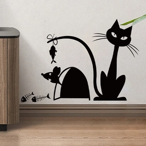 Detail of cat and mouse silhouette wall stickers on white wall above wooden baseboard