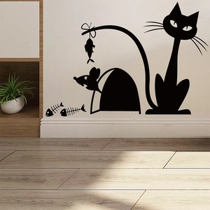 Detail of cute cat and mouse silhouette wall sticker on white baseboard in sunny room