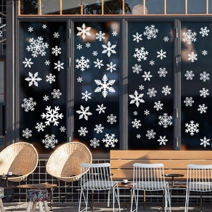 Close-up of white snowflake static window decals on a glass storefront in a cozy cafe setting